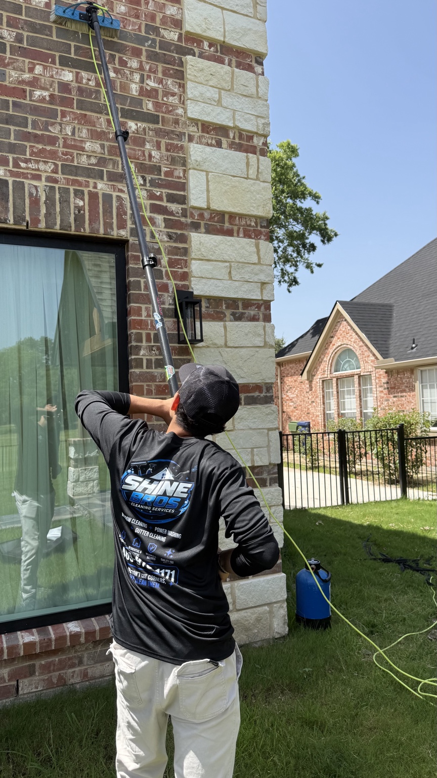 Shine Bros technician cleaning the exterior of a DFW home